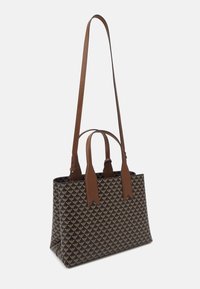 Taška přes rameno vyrobená z vzorované látky s tmavým pozadím a zlatými motivy, hnědými koženými uchy a nastavitelným ramenním popruhem.