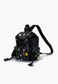 Zaino in pelle nera con superficie testurizzata, decorato con toppe colorate e borchie, chiusura a cordoncino e spallacci regolabili.