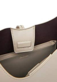 Borsa a mano in pelle beige chiaro con un design strutturato, dotata di chiusura magnetica, scomparto con zip e rivestimento in tessuto scuro.