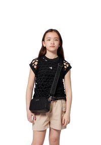 Top de malla negra con patrón geométrico, pantalones cortos beige y pequeño bolso negro cruzado con diseño acolchado y correa ajustable.