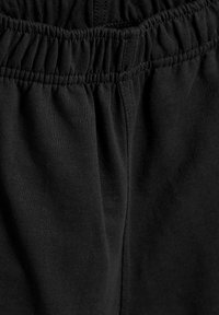 Ceinture élastique noire avec texture froncée ; tissu doux avec une surface lisse ; vue en gros plan mettant l'accent sur les détails du matériau.