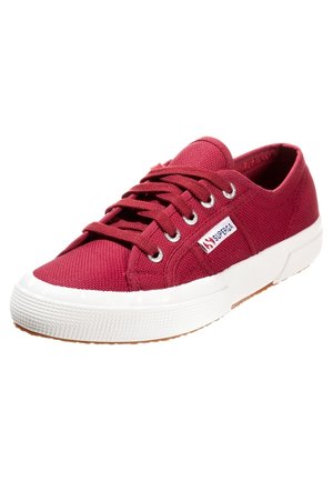 Baskets basses en toile rouge avec semelle en caoutchouc blanche et lacets, avec une petite étiquette logo "Superga" sur le côté.