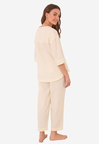Lichtgele lounge set met een loszittend shirt met korte mouwen en bijpassende tapered broek, beide van een textured stof met subtiele patronen.