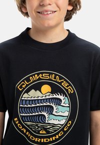Camiseta de algodón negra con un diseño gráfico redondo que presenta olas, montañas y un sol en colores azul, crema y amarillo.