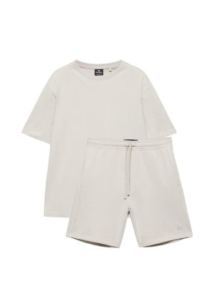 Béžové tričko s krátkym rukávom a okrúhlym výstrihom v páre s krátkymi nohavicami na elastickom páse so šnúrkou v rovnakom odtieni.