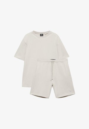 Tricou bej cu mâneci scurte și guler rotund, asortat cu pantaloni scurți cu talie elastică și șnur reglabil.