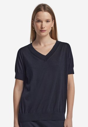 Maglia blu navy a maniche corte con scollo a V, polsini aderenti e orlo a costine. Realizzata in un tessuto liscio con una sottile lucentezza.