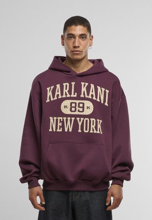 Bordová mikina s veľkým krémovým nápisom "KARL KANI 89 NEW YORK." Obsahuje predné vrecko a kapucňu so šnúrkou. Mäkká tkanina, voľný strih.