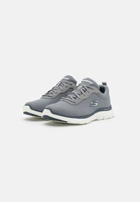 Gray mesh athletic shoes with a curved white sole, featuring a padded tongue and lace-up design, highlighted by a logo on the side.