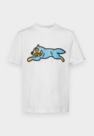 Balta kokvilnas T-kreklu ar zilu, multfilmu stila kaķi, kam ir dzeltena seja un asiem zobiem, kas novietots lēkšanas pozā.