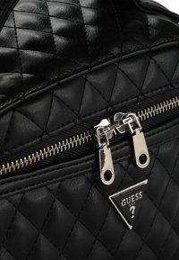 Borsa trapuntata nera con texture in pelle lucida, dotata di ferrature color argento, chiusura con doppia cerniera e un emblema logo triangolare.