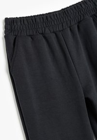 Sorte sweatpants med elastisk talje, sidelommer og et blødt, tekstureret stof for komfort.
