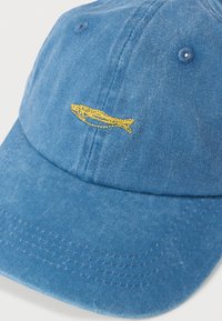 Sinise teksariidest nokats tekstuurse pinnaga, mille esiküljel on kollane tikitud kalamotiiv ja kontrastses toonis õmblused.