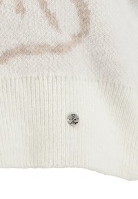 Pull en tricot crème clair avec un ourlet côtelé, présentant un motif beige subtil, et une étiquette en métal argenté avec "Ky Luu" dans le coin inférieur.