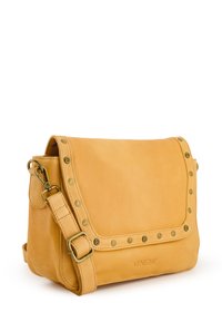 Gul læder crossbody taske med en flad topklap, dekorative nitter langs kanterne, justerbar rem og præget logo på forsiden.