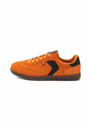 Zapatilla de ante naranja con acentos negros, puntera redonda, suela de goma plana y diseño de cordones. Cuenta con una superficie texturizada y una marca minimalista.