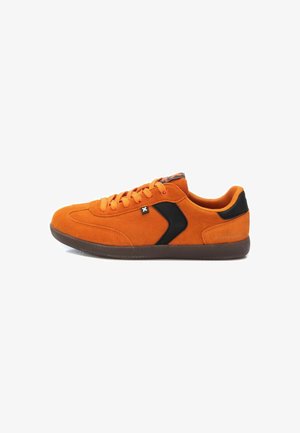 Zapatilla de ante naranja con acentos negros, puntera redonda, suela de goma plana y diseño de cordones. Cuenta con una superficie texturizada y una marca minimalista.