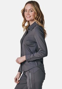 Gray button-up shirt with a collar, made of smooth material. Features long sleeves, a fitted design, and a curved hemline.