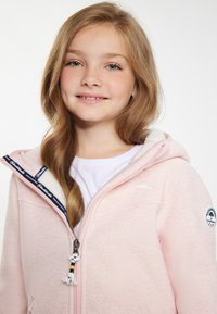 Ljust rosa zip-up hoodie med en texturerad yta, fleecefodrad huva, blå och vit mönstrad dragkedja och broderad logotyp på ärmen.
