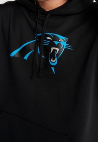 Schwarzer Hoodie mit einem blauen und grauen Carolina Panthers-Logo auf der Brust. Weicher Stoff mit einer Fronttasche und verstellbarem Kordelzug an der Kapuze.