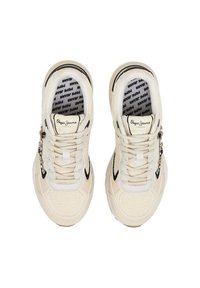 Sneakers beige con una parte superiore in rete testurizzata, accenti neri e lacci bianchi. Presentano un logo e hardware decorativo sul lato.