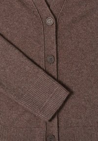 Brun kofta tillverkad av mjukt stickat tyg, med V-ringning, tre knappar, ribbade ärmslut och en texturerad yta.