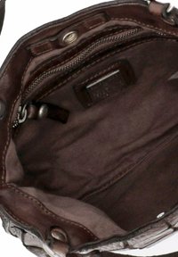 Interno di borsa a tracolla in pelle marrone caratterizzato da una texture liscia, tasca con cerniera e diversi scomparti rivestiti in morbido tessuto.