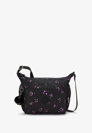 Sort crossbody taske med små lilla og hvide blomster, frontlommesyning, justerbar rem og en fluffy sort nøglering.
