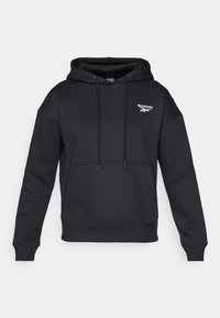 Crna dukserica s kapuljačom izrađena od mekog, teksturiranog materijala. Ima prednji džep i bijeli Reebok logo na prsima.