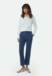 Witte overhemd met lange mouwen, gecombineerd met blauwe denim broek en zilveren platte schoenen. Eenvoudig ontwerp en klassieke pasvorm.