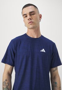 Navy blue athletic t-shirt with a textured pattern, short sleeves, crew neck, and a white Adidas logo printed on the left chest.
