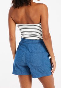 Denim shorts with an elastic waistband, two back pockets, and a casual fit. Paired with a striped, strapless top for a relaxed look.