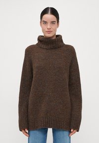 Brauner Strickpullover mit hohem, geripptem Rollkragen. Lässiger Schnitt, lange Ärmel und gerippter Saum. Weicher Stoff mit dezenten Farbvariationen.