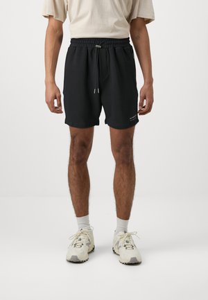 Schwarze Baumwollshorts mit einem elastischen Bund und einem Kordelzug. Das Design umfasst seitliche Taschen und ein kleines Logo am unteren Saum.