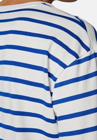 Blå och vit randig stickad tröja med en mjuk textur, avslappnad passform och rund halsringning, med jämna horisontella ränder.