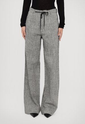 Szare spodnie o szerokich nogawkach z czarnym ściągaczem w pasie, noszone z czarnymi butami w szpic i dopasowaną czarną bluzką z długim rękawem.