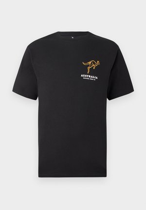 Juoda trumpomis rankovėmis marškinėliai su mažuoju geltonu kengūros logotipu ir "AUSTRALIJA RIP CURL SURF CO" tekstu kairėje krūtinės pusėje.