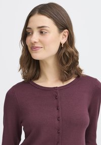 Burgunderfarbener Strickcardigan mit rundem Halsausschnitt, langen Ärmeln und Knopfverschluss an der Vorderseite. Weiche Textur mit bequemem Sitz.