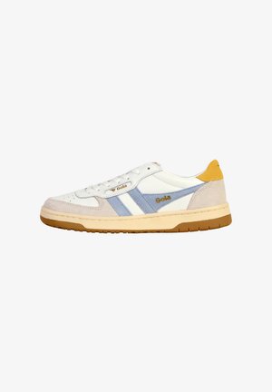 Zapatilla blanca con acentos en azul claro y beige. Cuenta con una suela de goma, parte delantera con cordones y una lengüeta en el talón de color amarillo. Branding estilizado de Gola visible.