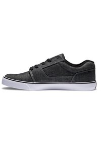 Zapatillas de lona negras con un diseño de perfil bajo, suela de goma blanca y cordones negros. Presentan un acabado texturizado y costuras en contraste.