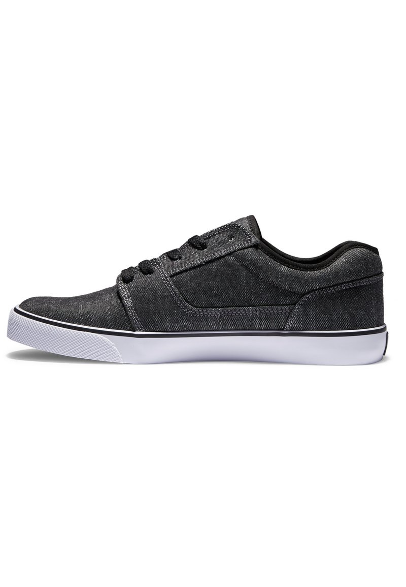 Zapatillas de lona negras con un diseño de perfil bajo, suela de goma blanca y cordones negros. Presentan un acabado texturizado y costuras en contraste.