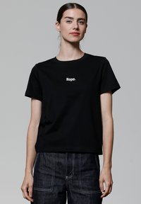 Schwarzes Baumwoll-T-Shirt mit kurzen Ärmeln, das auf der Vorderseite den weißen Drucktext „Nope.“ zeigt. Klassisches Rundhalsausschnitt-Design.