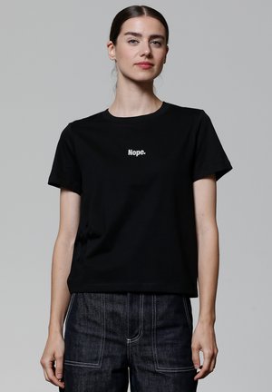 T-shirt en coton noir à manches courtes avec un texte imprimé blanc "Nope." sur le devant. Design classique à col rond.