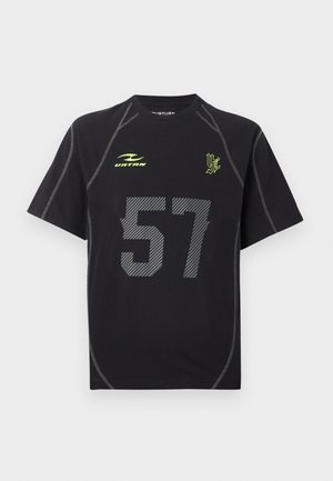 Μαύρο αθλητικό μπλουζάκι με κοντά μανίκια και γκρι ραφές, μεγάλο γκρι νούμερο 57, κίτρινο λογότυπο "VATAN" και κίτρινο στυλιζαρισμένο έμβλημα "VF" στο στήθος.