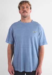 T-shirt in cotone blu con vestibilità rilassata, maniche corte e collo tondo. Presenta un logo sottile sul petto e una texture morbida.