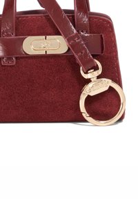 Burgundy suede handbag with glossy leather straps, gold-tone hardware, oval clasp, and a metal keyring accent attached.