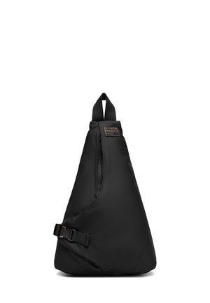 Czarna trójkątna torebka na ramię z regulowanym paskiem na klamrę i górnym uchwytem, z małą prostokątną metką marki blisko góry.