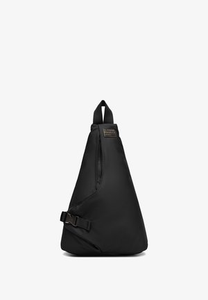 Czarna trójkątna torebka na ramię z regulowanym paskiem na klamrę i górnym uchwytem, z małą prostokątną metką marki blisko góry.