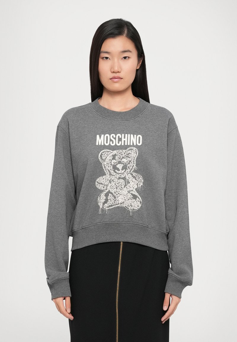Felpa grigia con design accorciato, maniche lunghe, polsini a coste e un grafico di un orso bianco. Il testo "Moschino" è stampato sopra il design.