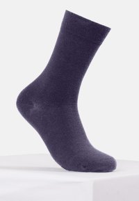 Calzino viola realizzato in morbido tessuto, con una lunghezza standard alla caviglia e una superficie liscia, priva di motivi o decorazioni visibili.